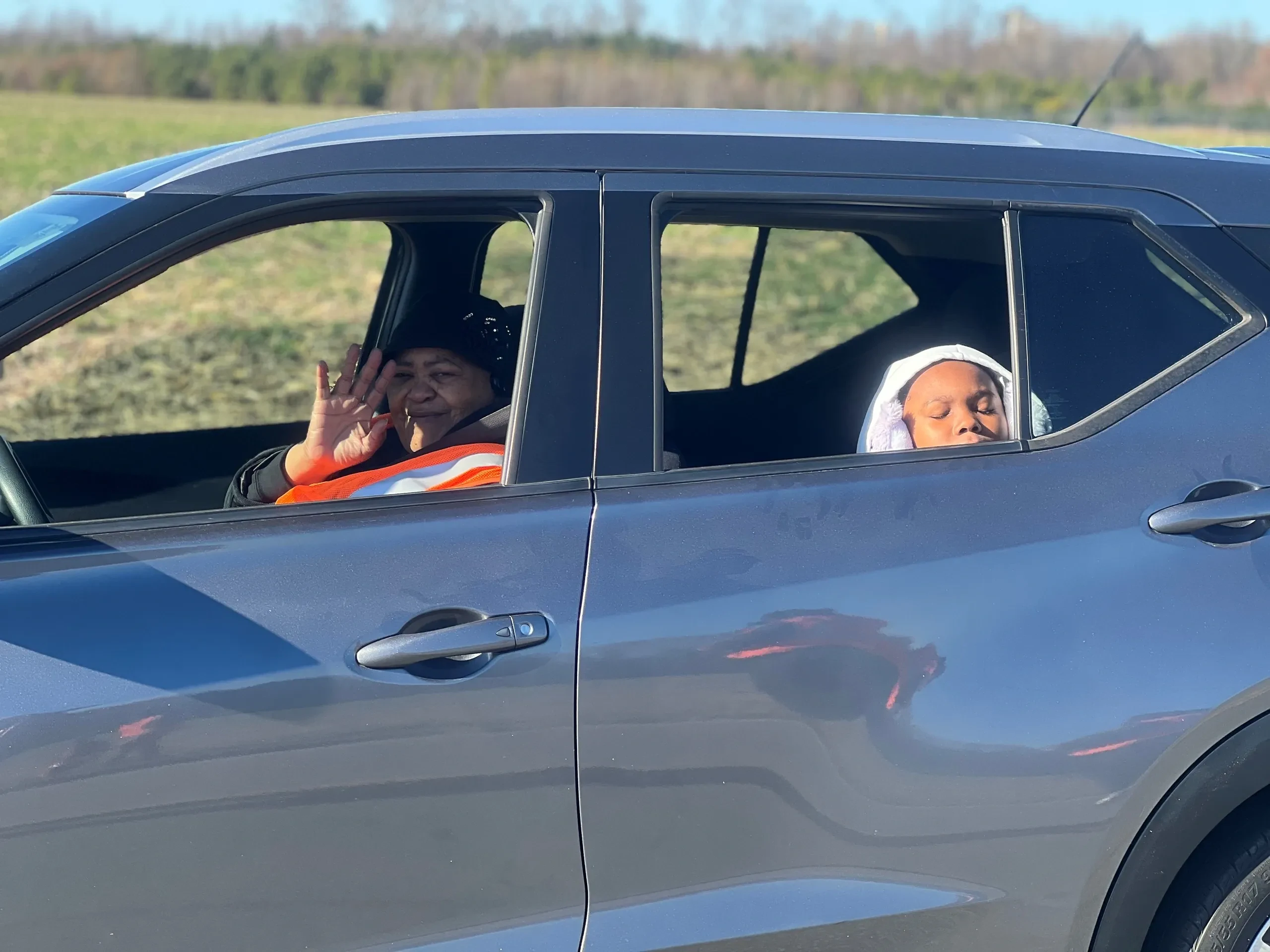 Hand of the King community members riding in a blue vehicle during an outreach event