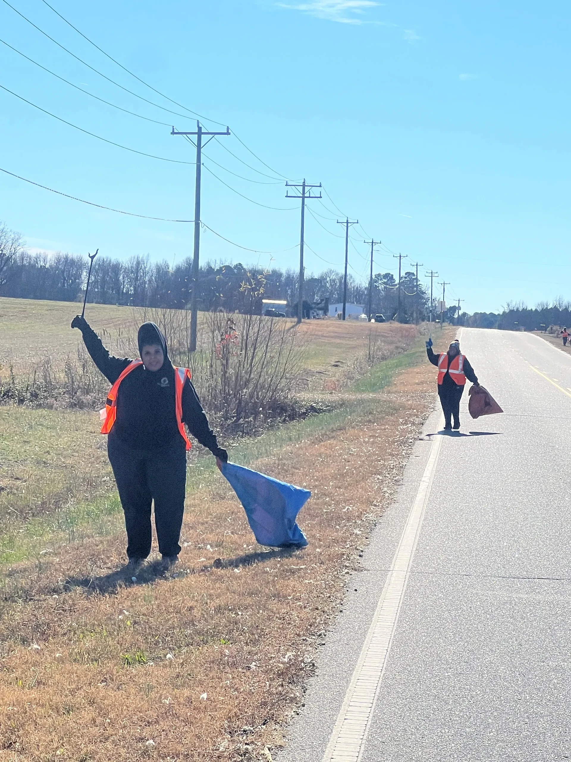 Volunteers collecting litter along the roadside during an Adopt-a-Highway cleanup