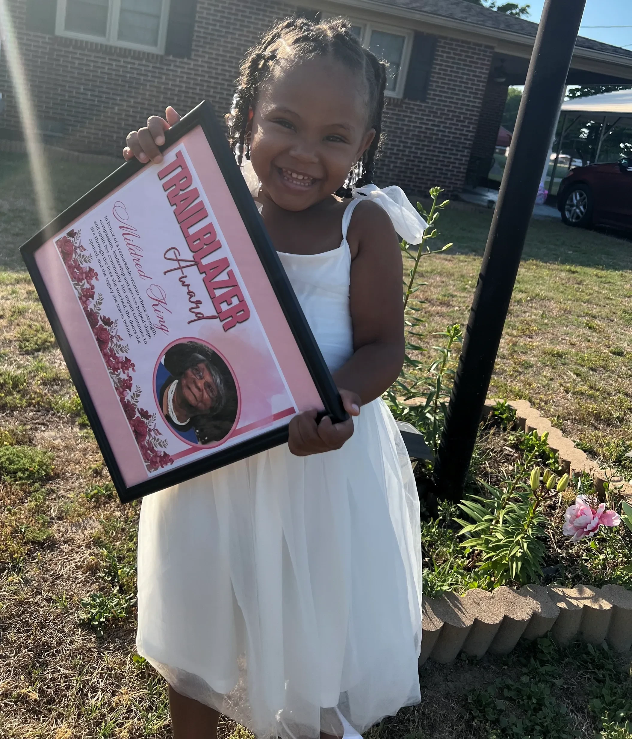 Young child holding a framed tribute portrait outdoors