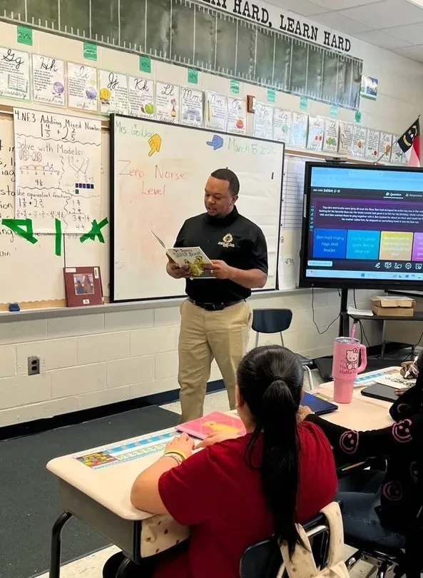 Hand of the King volunteer reading to students in a classroom