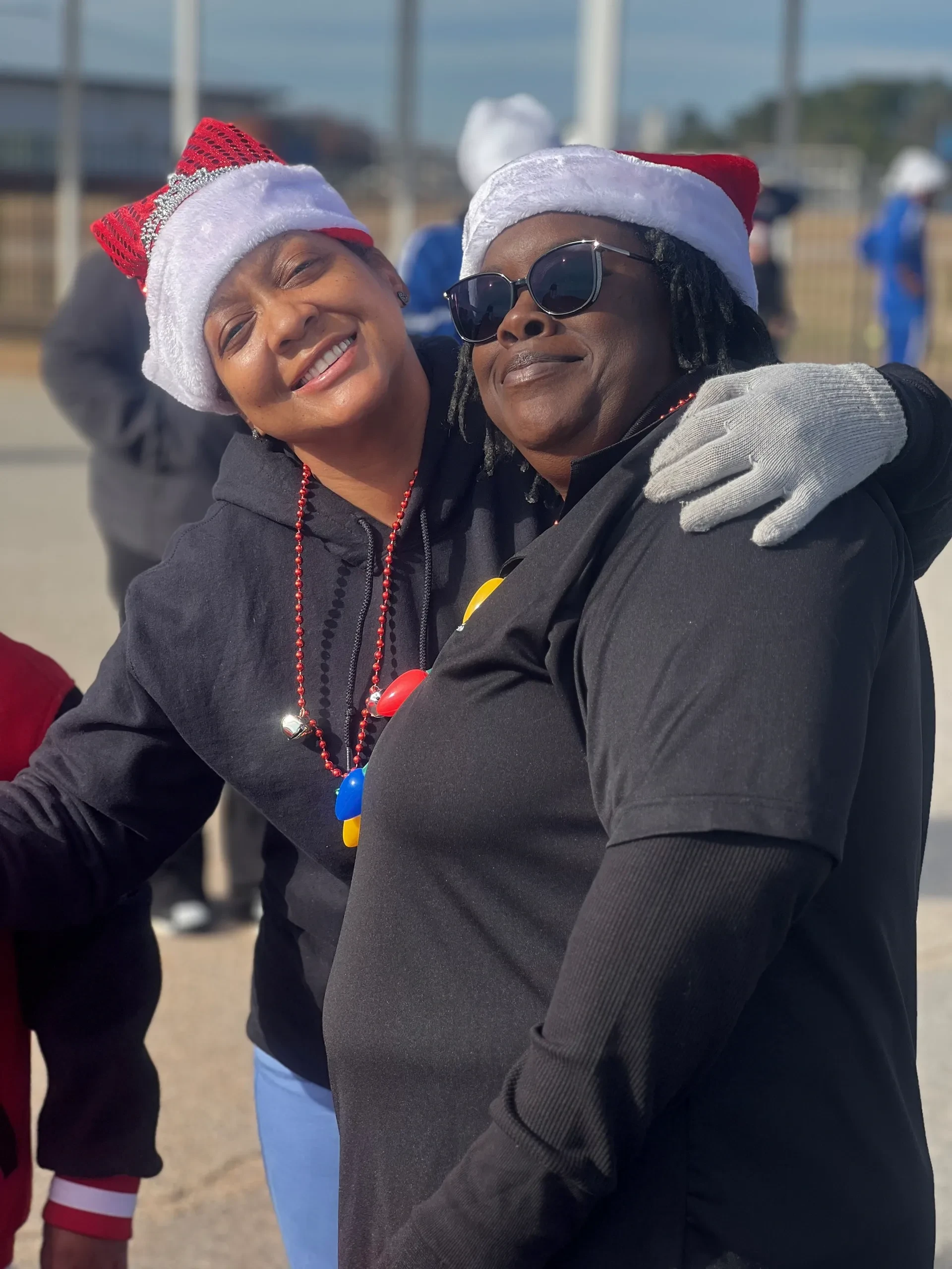 Two Hand of the King volunteers smiling together in festive holiday hats