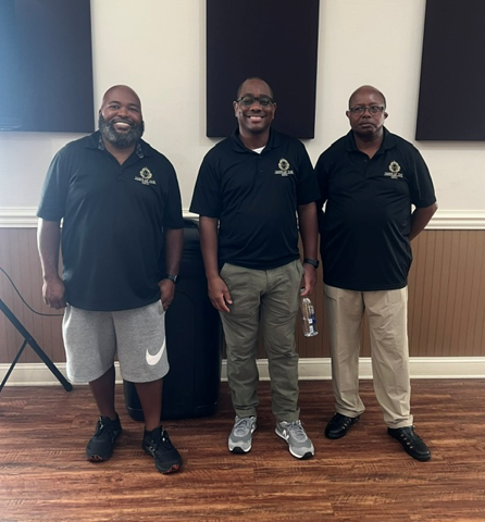 Three Hand of the King volunteers in branded polo shirts at the Clothing Giveaway