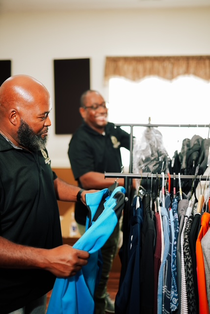 Two Hand of the King volunteers sorting clothing on a rack at the Clothing Giveaway
