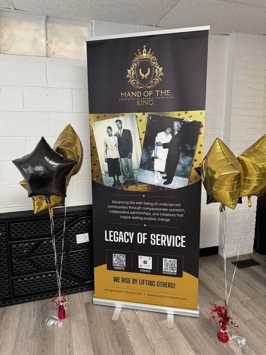 Hand of the King Legacy of Service banner with gold and black star balloons at the King's Pantry dedication