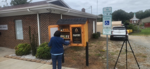 Community member viewing the open King's Pantry stocked with food and supplies