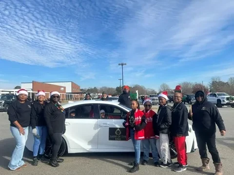 Hand of the King community group gathered outdoors beside a white vehicle