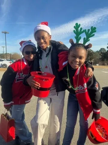 Three children in festive holiday outfits at a community parade