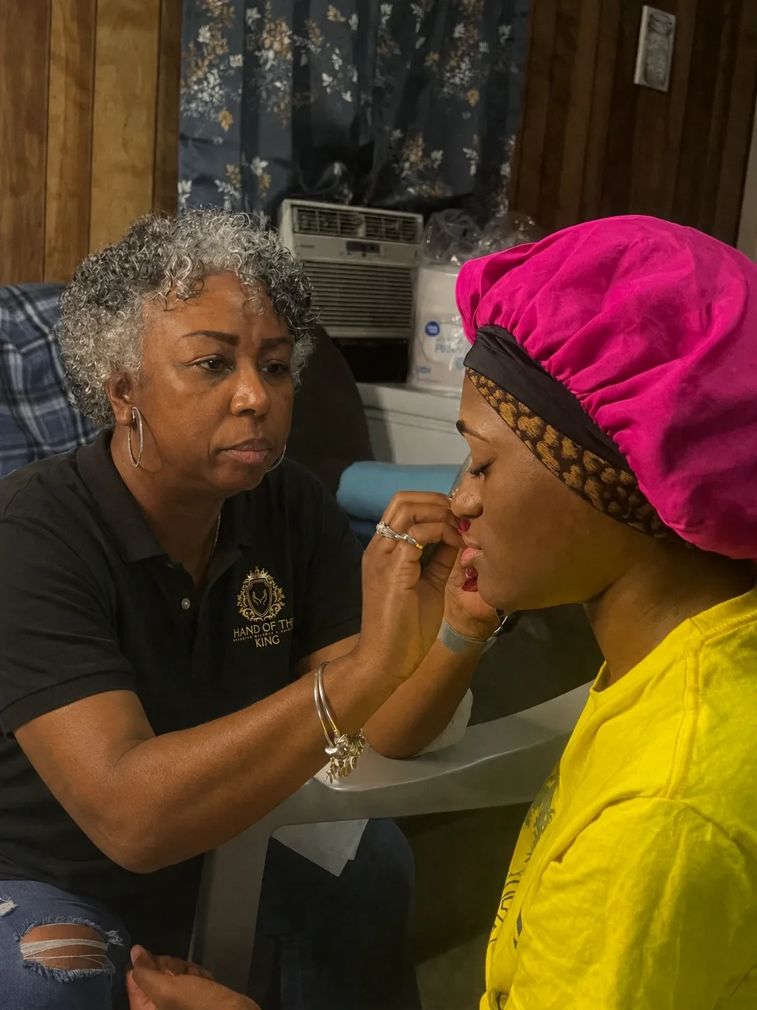 Hand of the King volunteer providing makeup service to a community member