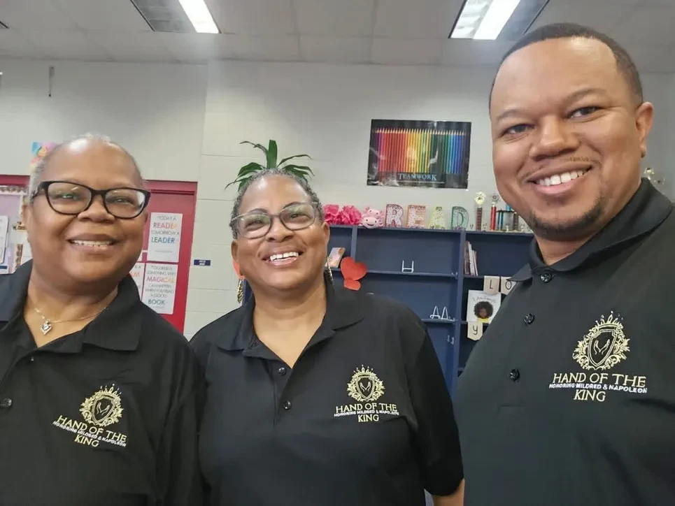 Three Hand of the King volunteers in matching polo shirts at a reading outreach