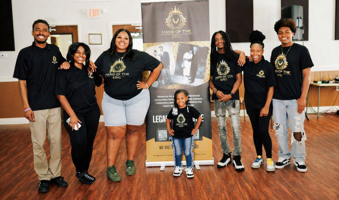 Junior Advisory Council - G3s group photo beside the Hand of the King Legacy of Service banner